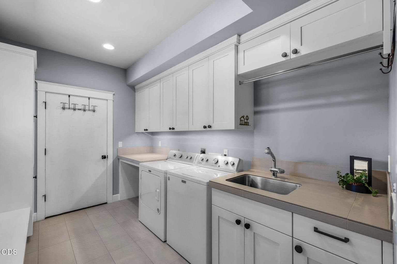 Well-appointed laundry room with sink, extensive cabinetry, generous folding space, and convenient built-in storage.