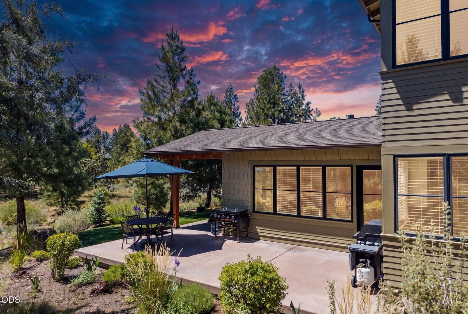 Inviting rear patio with covered outdoor living, timber detailing, lawn, mature landscaping, and warm evening light for effortless entertaining.