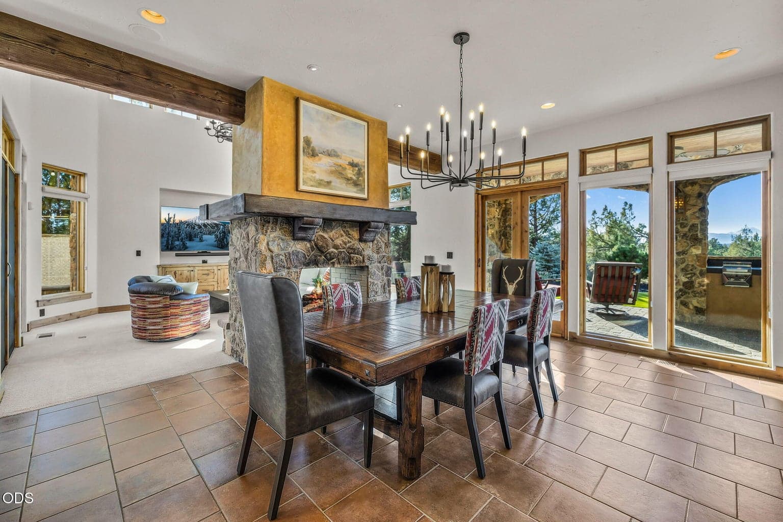 A beautiful new chandelier enhances the airy dining space, while the double-sided stone fireplace connects seamlessly to a comfortable sitting area beyond.