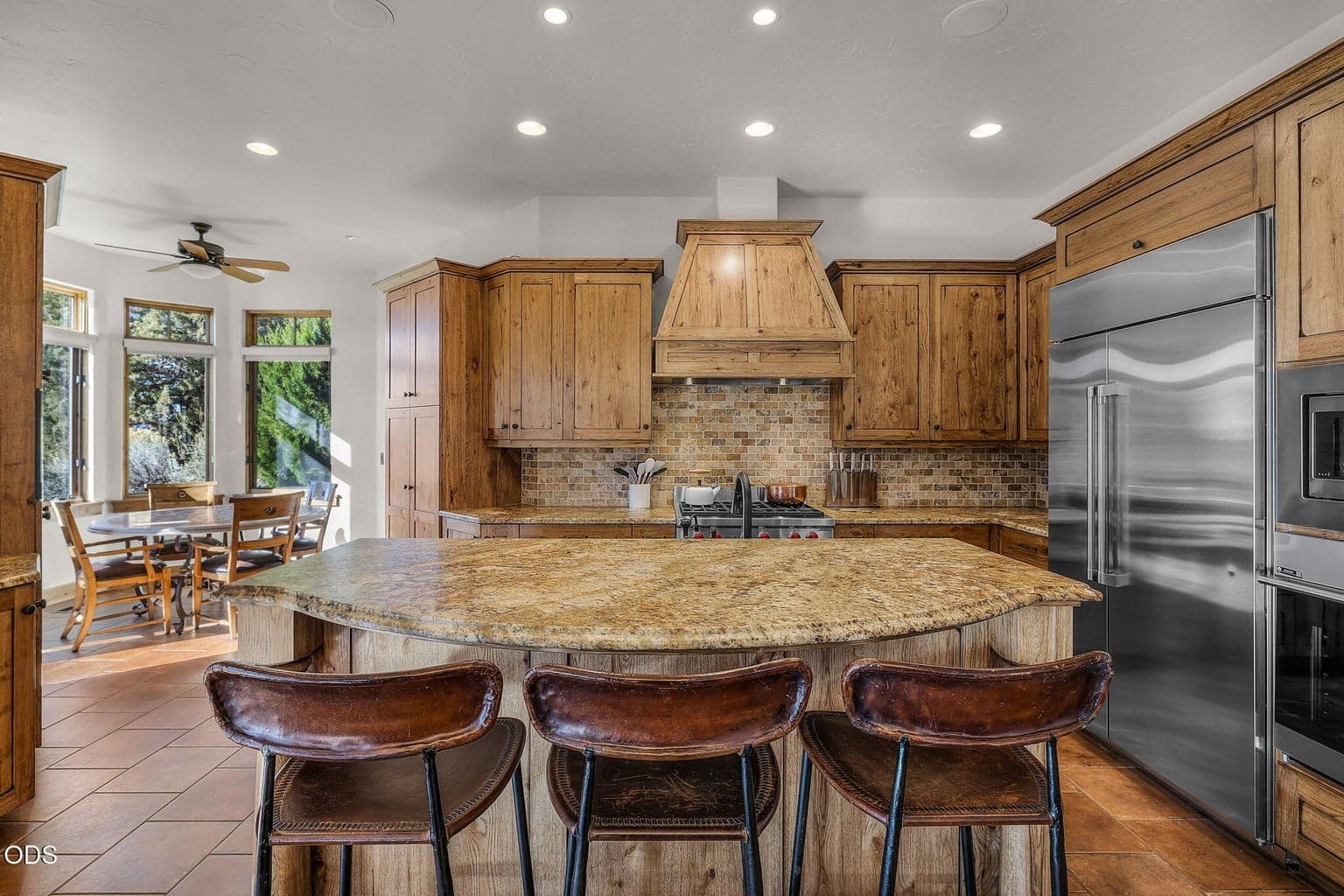 A spacious kitchen offering granite countertops, full-height tile backsplash, a large island, under-cabinet lighting, and a light-filled breakfast nook