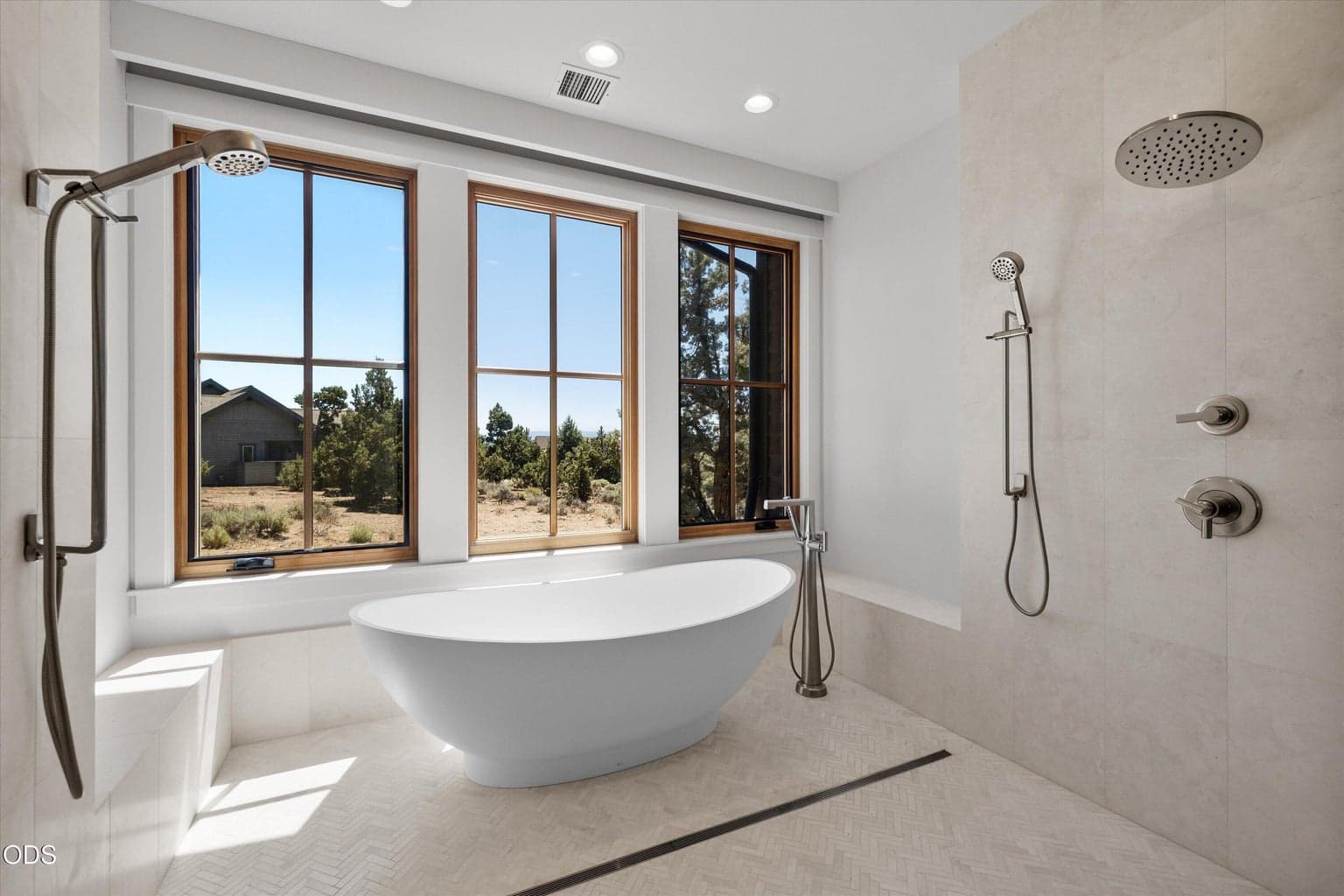Glass-enclosed wet room features a multi-head shower system and deep-soaking tub for a spa experience