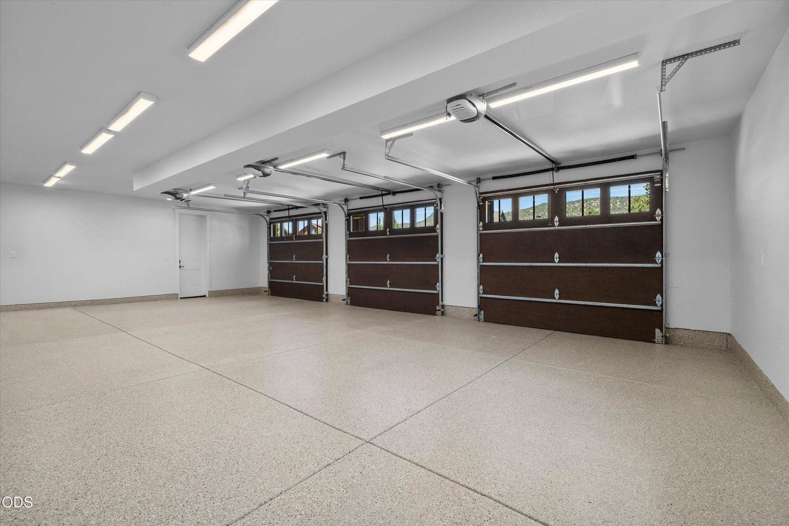3-car garage with storage closet, door to yard, and door to covered hidden trash area.