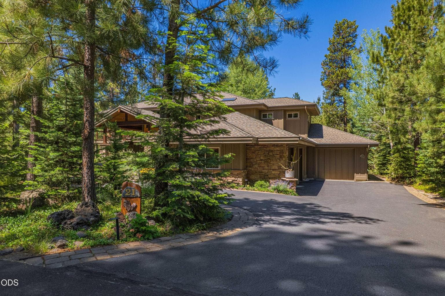 Private approach to 57733 Wallowa Lane in Sunriver, with mature trees, a paved drive, natural landscaping, and a striking Sun Forest-built home tucked into a spectacular private setting.