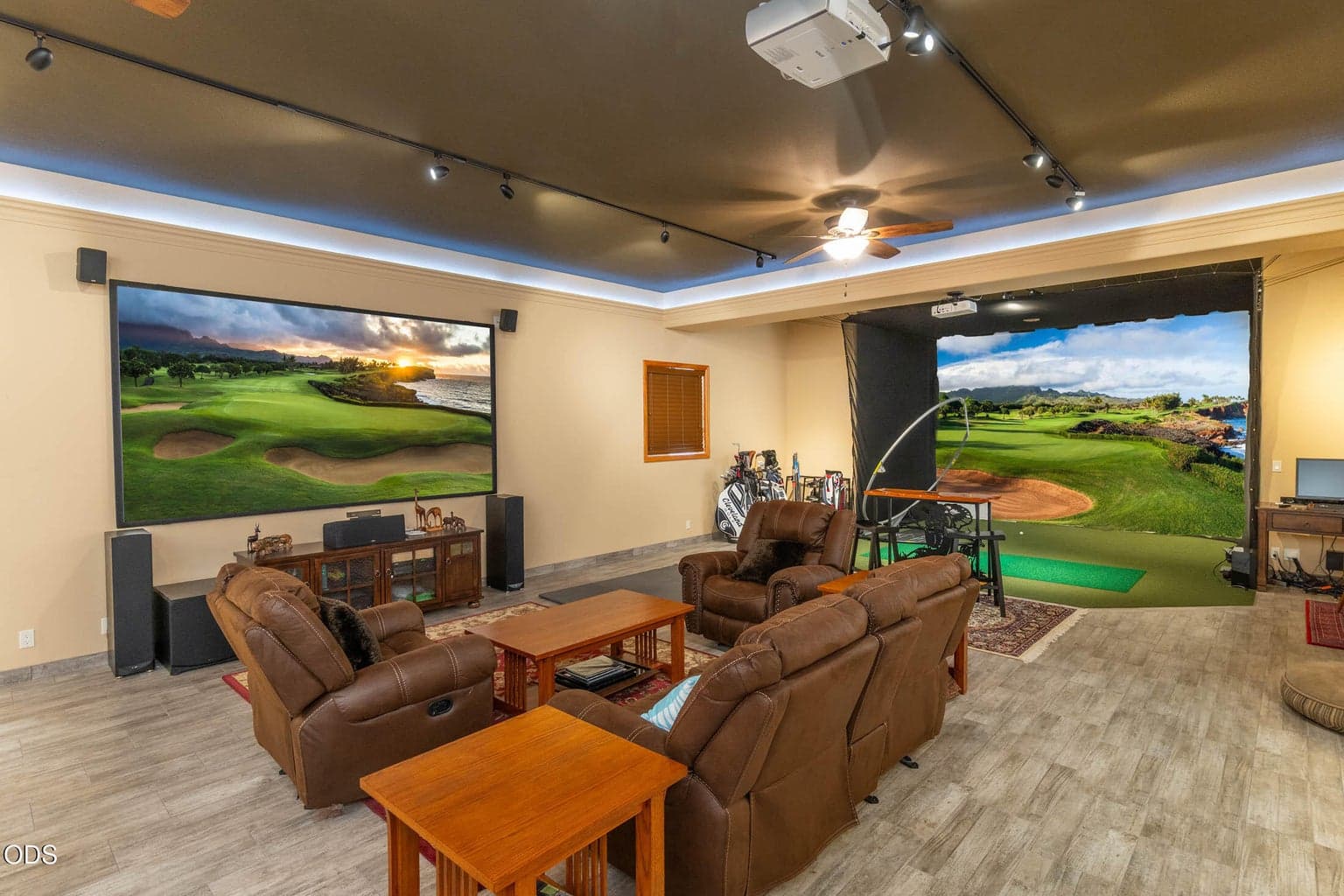View of the 1200 sq. ft. flex room with Golf Simator equipment, ball hitting mat and screen as well as the large theatre TV and sofas