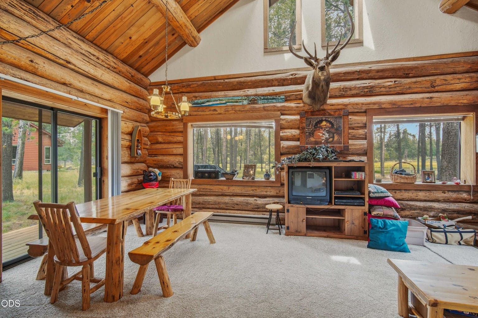 Vaulted wood ceilings, log walls, large windows, and a wood stove create a warm gathering space after a day on the river or trails.