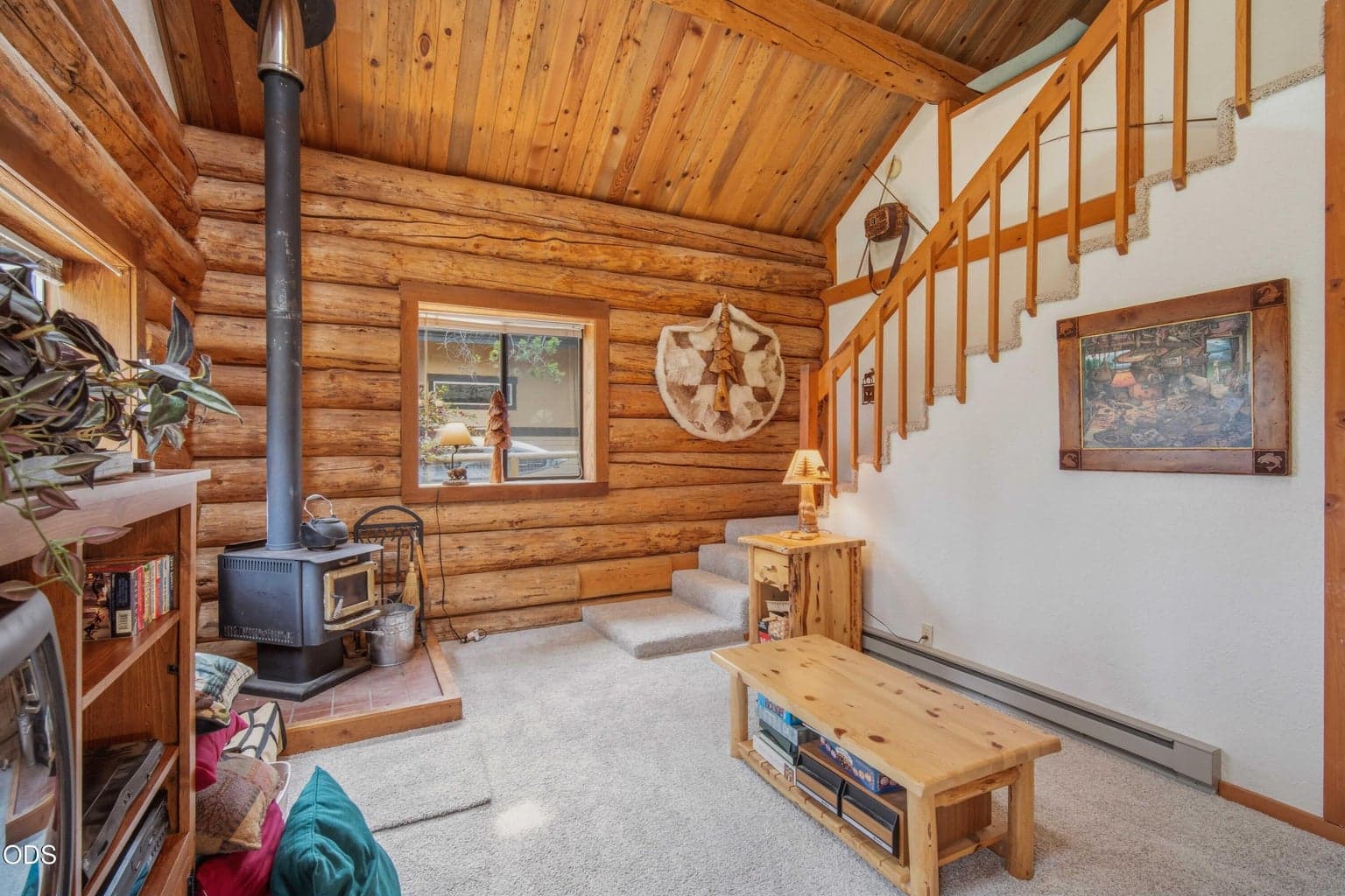 The living area flows toward the dining space and stairs to the upper loft, creating an open and comfortable cabin layout.