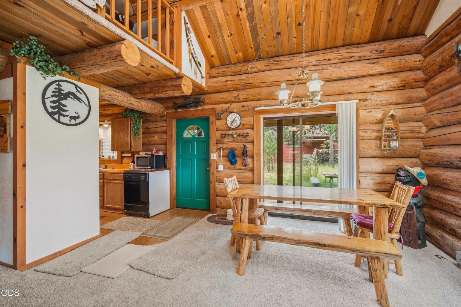 The dining area sits beside the green front door and sliding glass door, creating an easy connection between indoor and outdoor living.