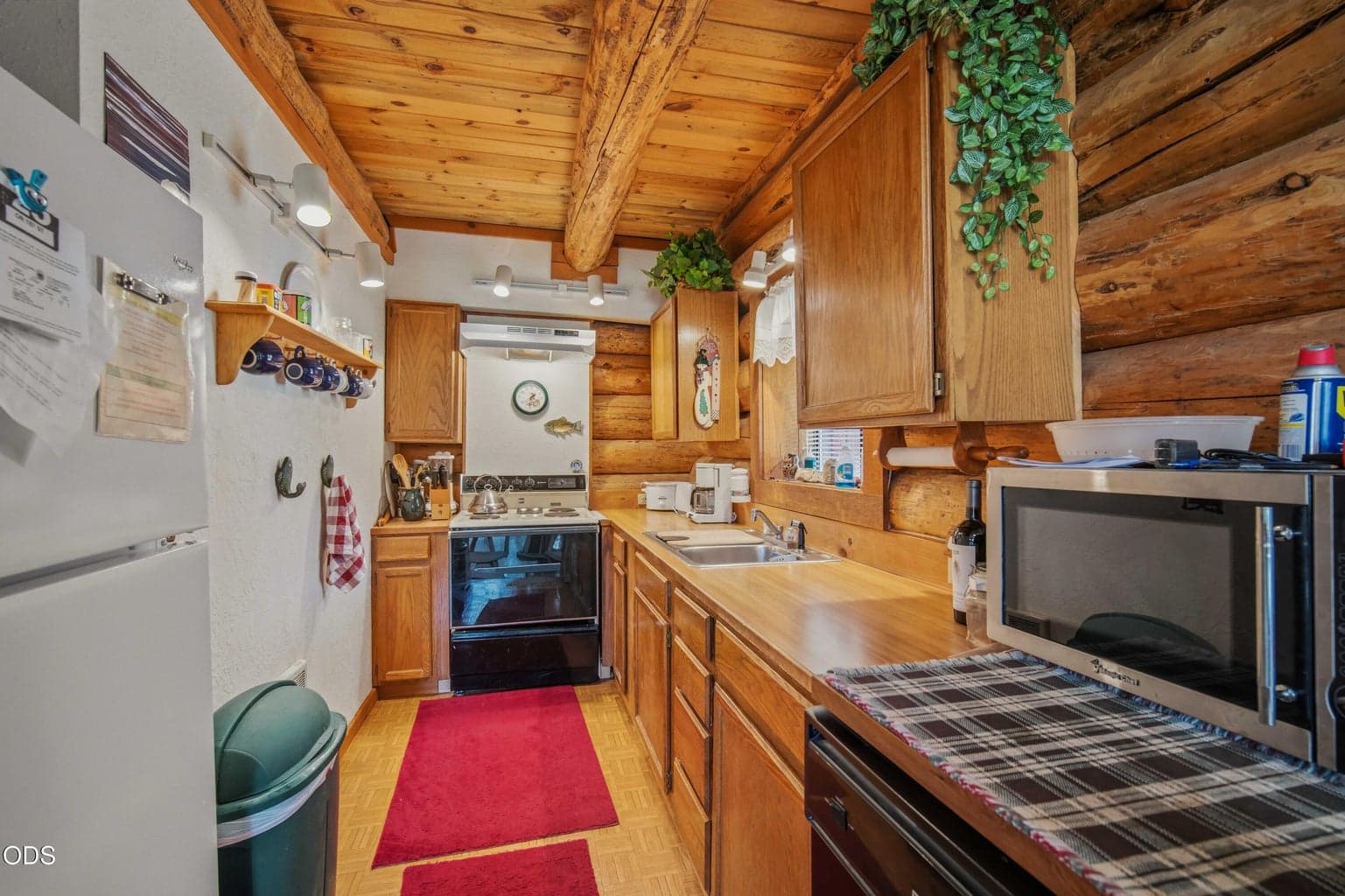 The efficient cabin kitchen features wood cabinetry, warm log accents, and everything close at hand for weekends or extended stays.