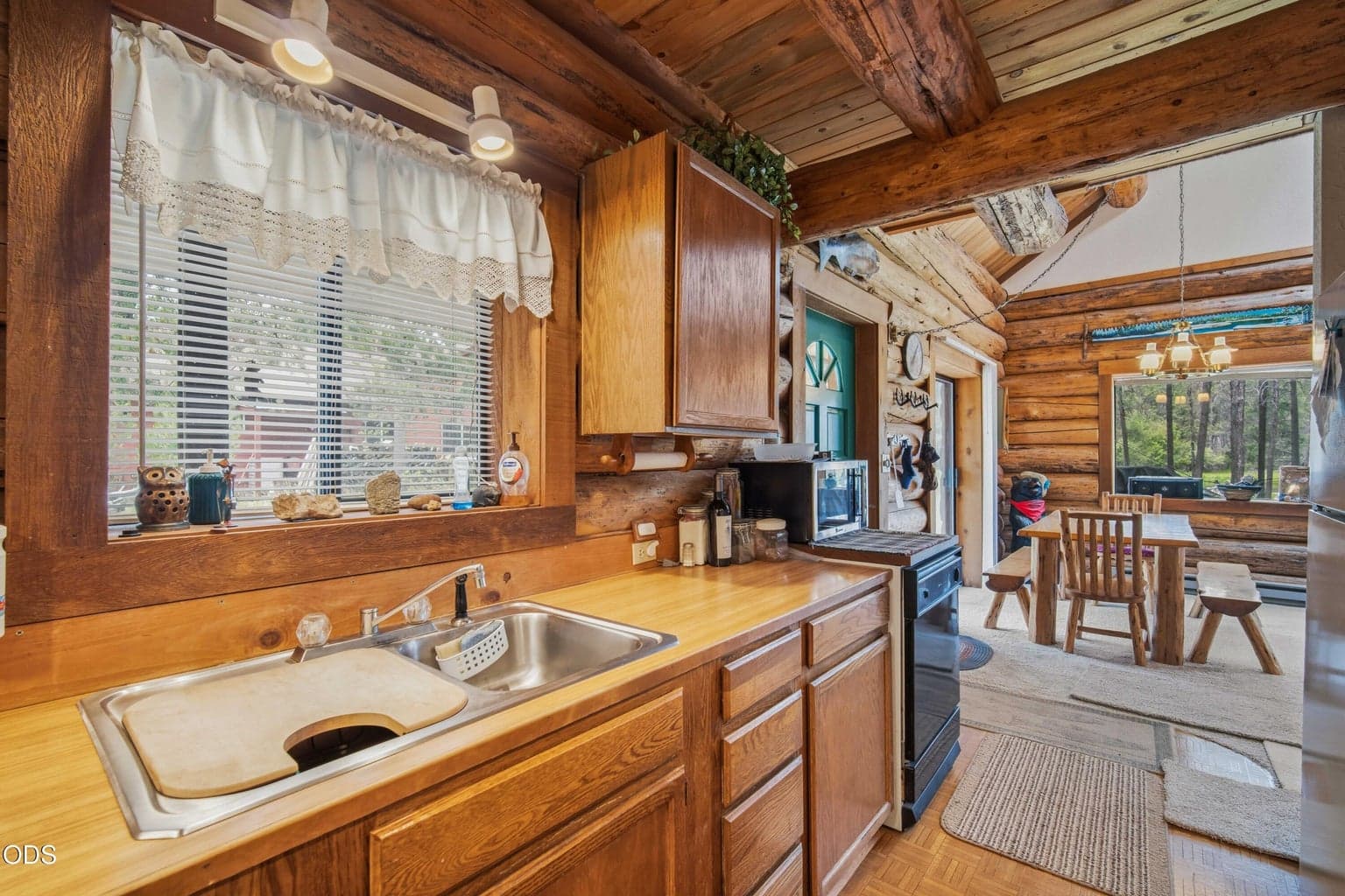 From the kitchen, the dining area and vaulted living space remain open and connected for relaxed cabin gatherings.