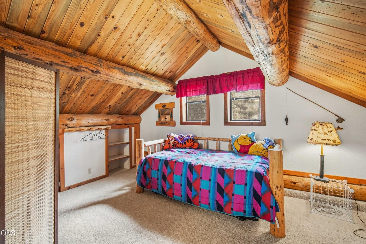 Exposed beams, wood ceilings, and natural light give the upper loft the charm of a true cabin sleeping space.