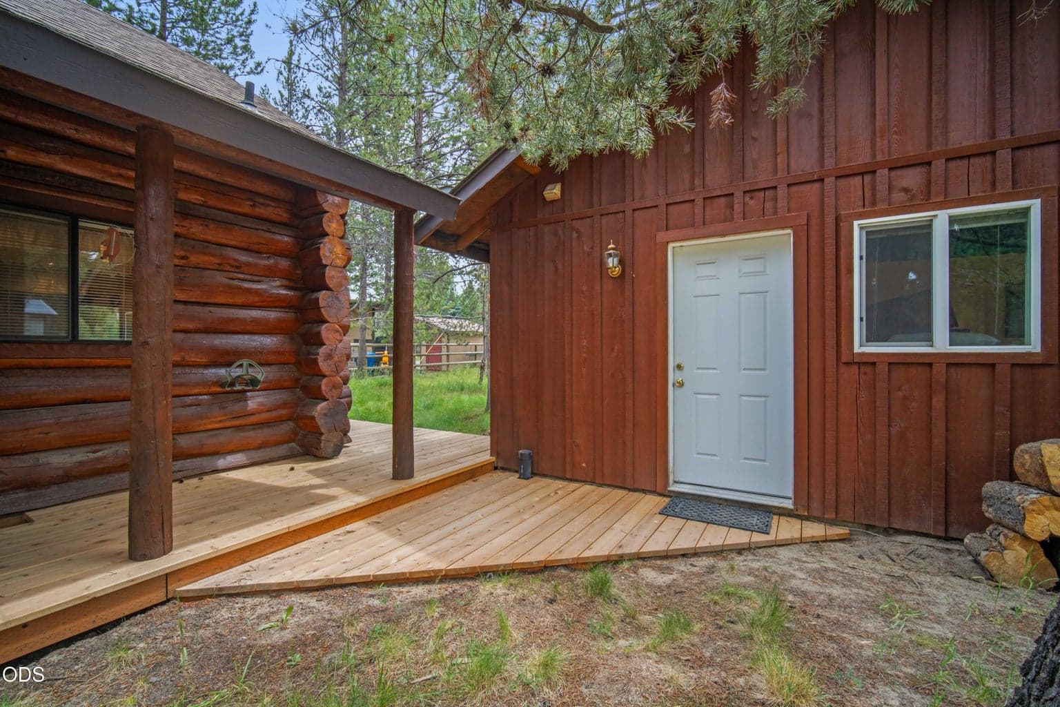 The fully replaced deck connects the main log cabin with the separate conditioned guest bedroom and bathroom behind the garage.