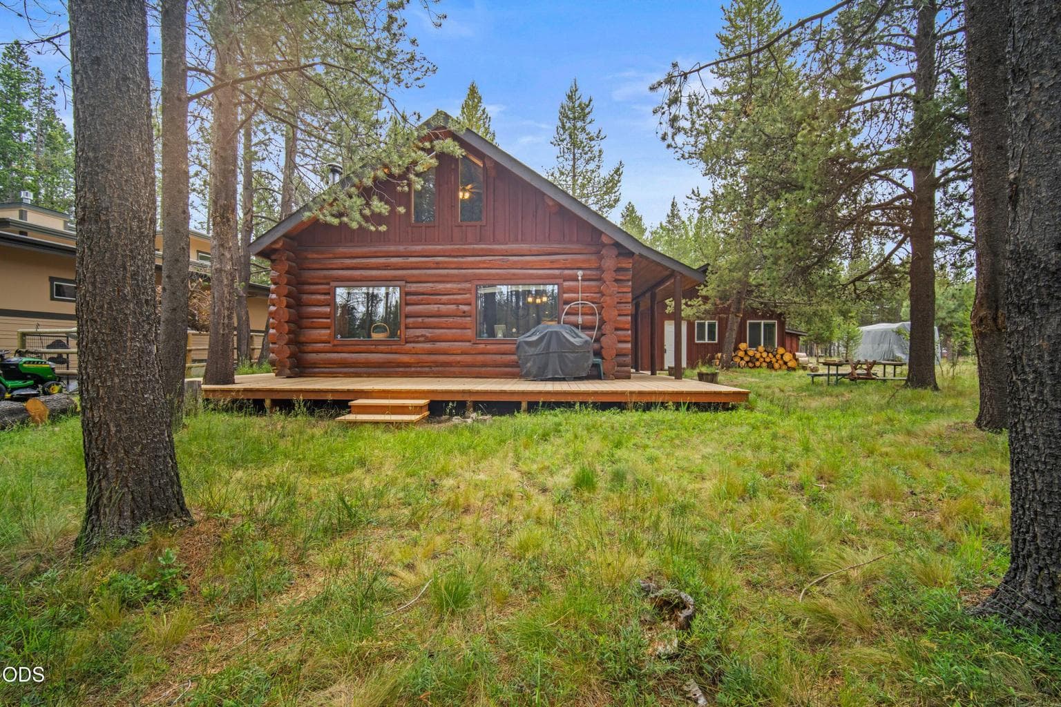 The rear deck extends the living space outdoors, surrounded by mature trees and the natural landscape of the Big Deschutes River corridor.