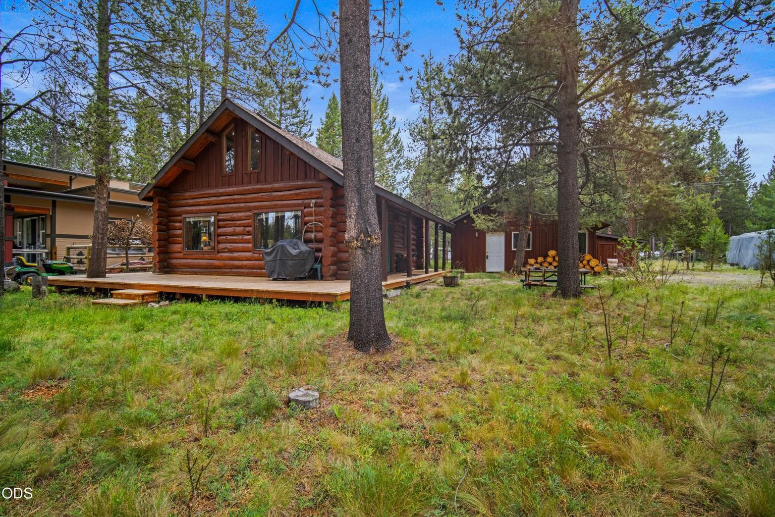 The cabin, detached garage, guest space, and connecting decks sit comfortably within the natural wooded riverfront lot.
