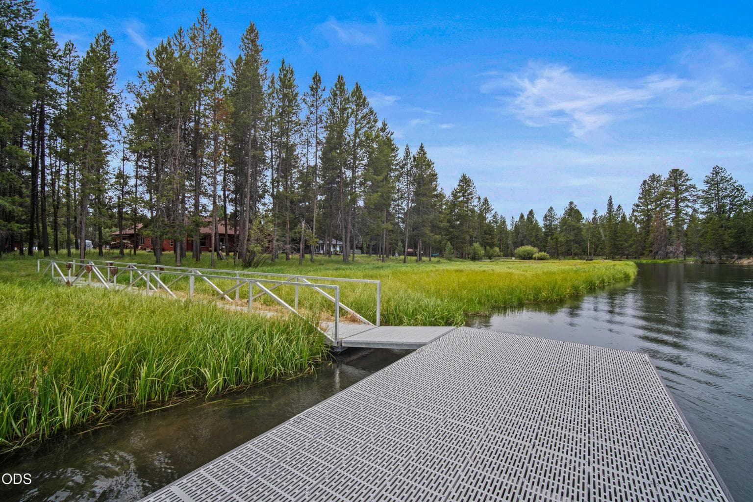 From the river, the long dock walkway leads back toward the cabin, which is privately set among the trees.