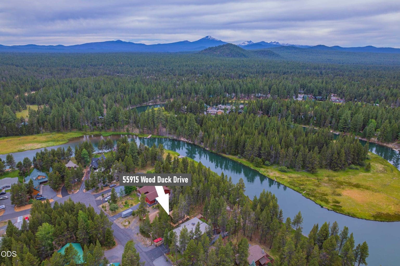 A broader aerial view places the property within the winding Big Deschutes River corridor, with Central Oregon forest and Cascade mountain views beyond.