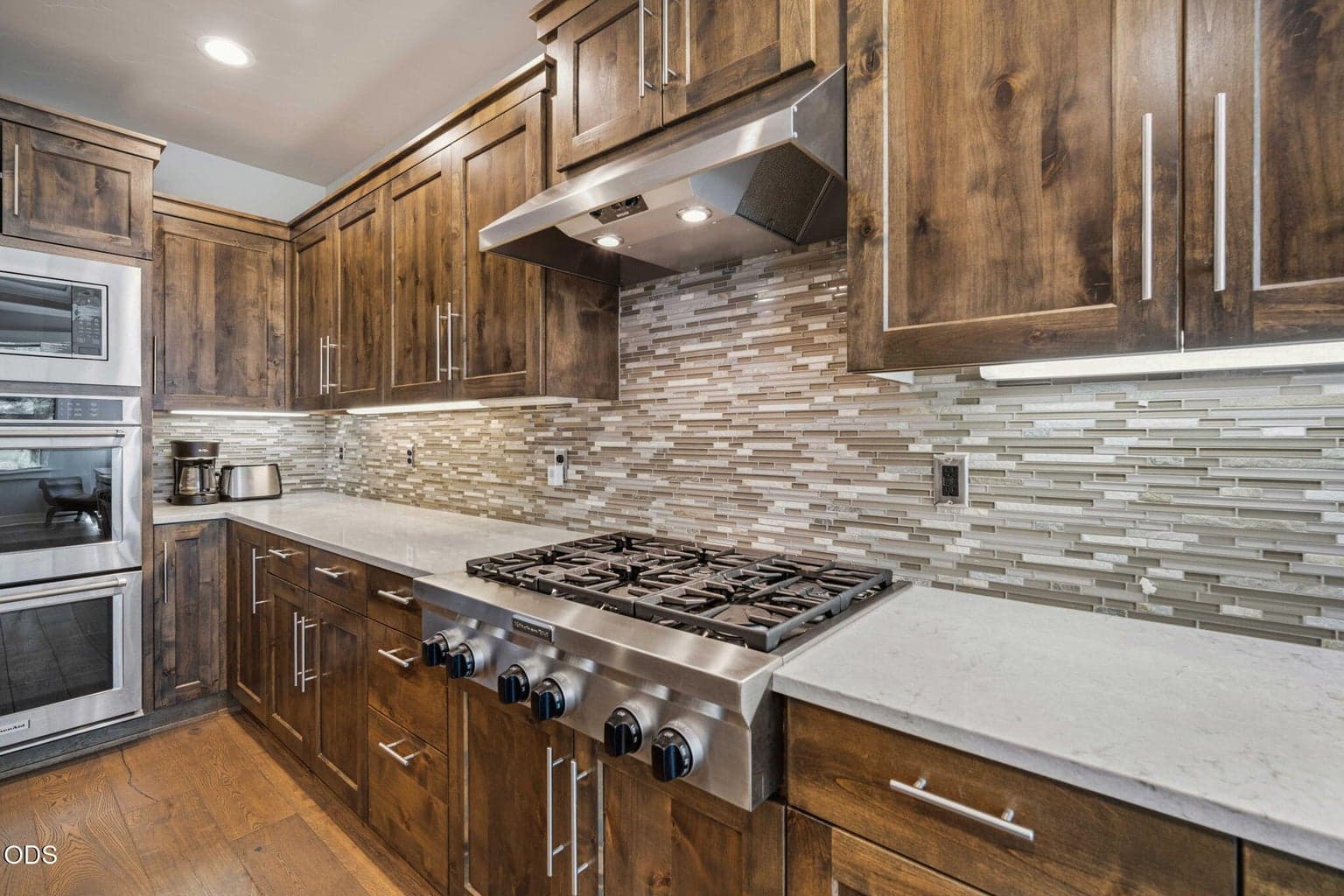 Chef’s kitchen with custom wood cabinetry, gas cooktop, and tile backsplash.