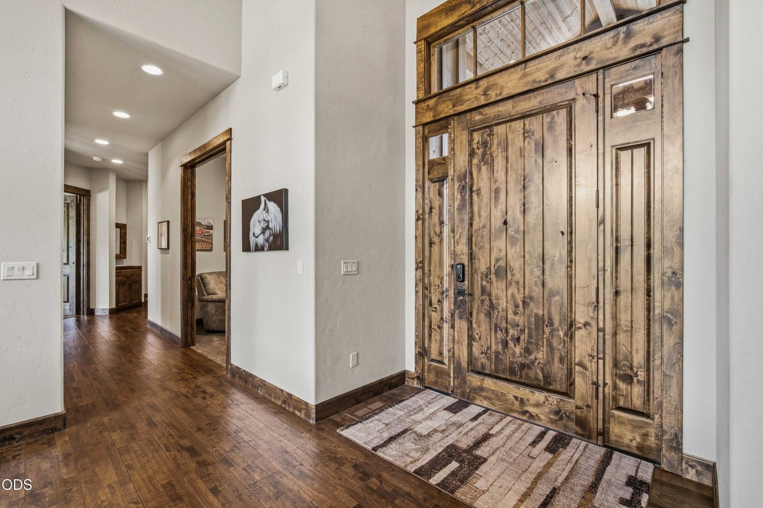 The entry opens to warm wood floors, substantial trim, and a thoughtful interior palette that complements the home’s natural surroundings without competing with the setting.