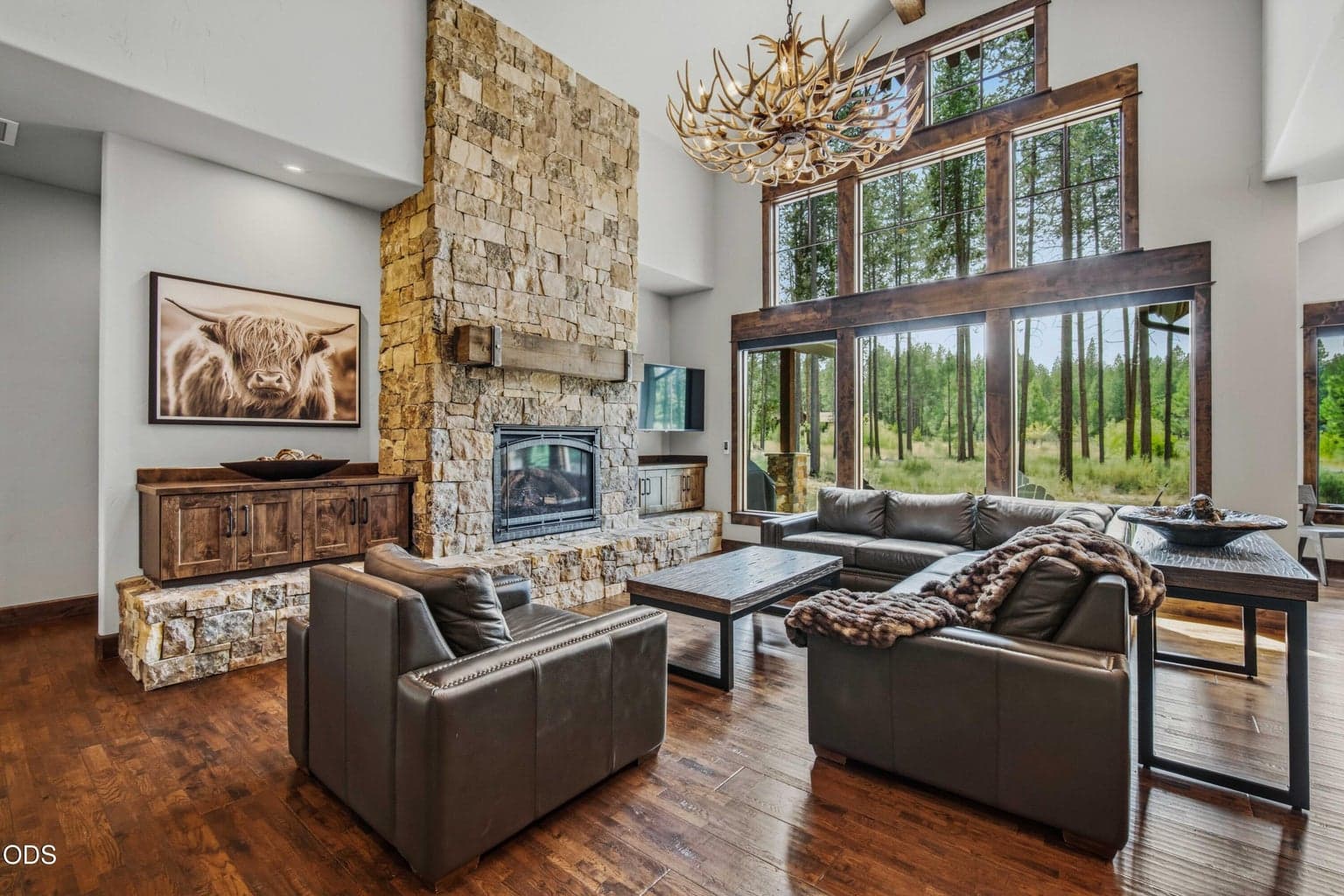 Anchored by a dramatic stone fireplace and warm wood detailing, the great room offers a refined yet relaxed gathering space designed to embrace the extraordinary setting just outside.