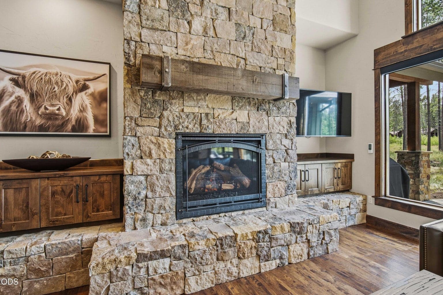 The stone fireplace, substantial wood mantel, and built-in cabinetry create a strong sense of craftsmanship, balancing luxury finishes with the natural materials of a private Northwest retreat.