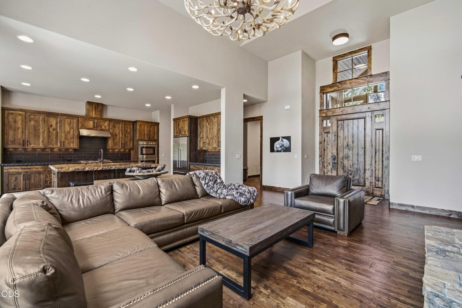 Warm wood tones, soaring ceilings, and an open connection between living, dining, and kitchen spaces create an inviting interior that feels refined, comfortable, and rooted in its setting.