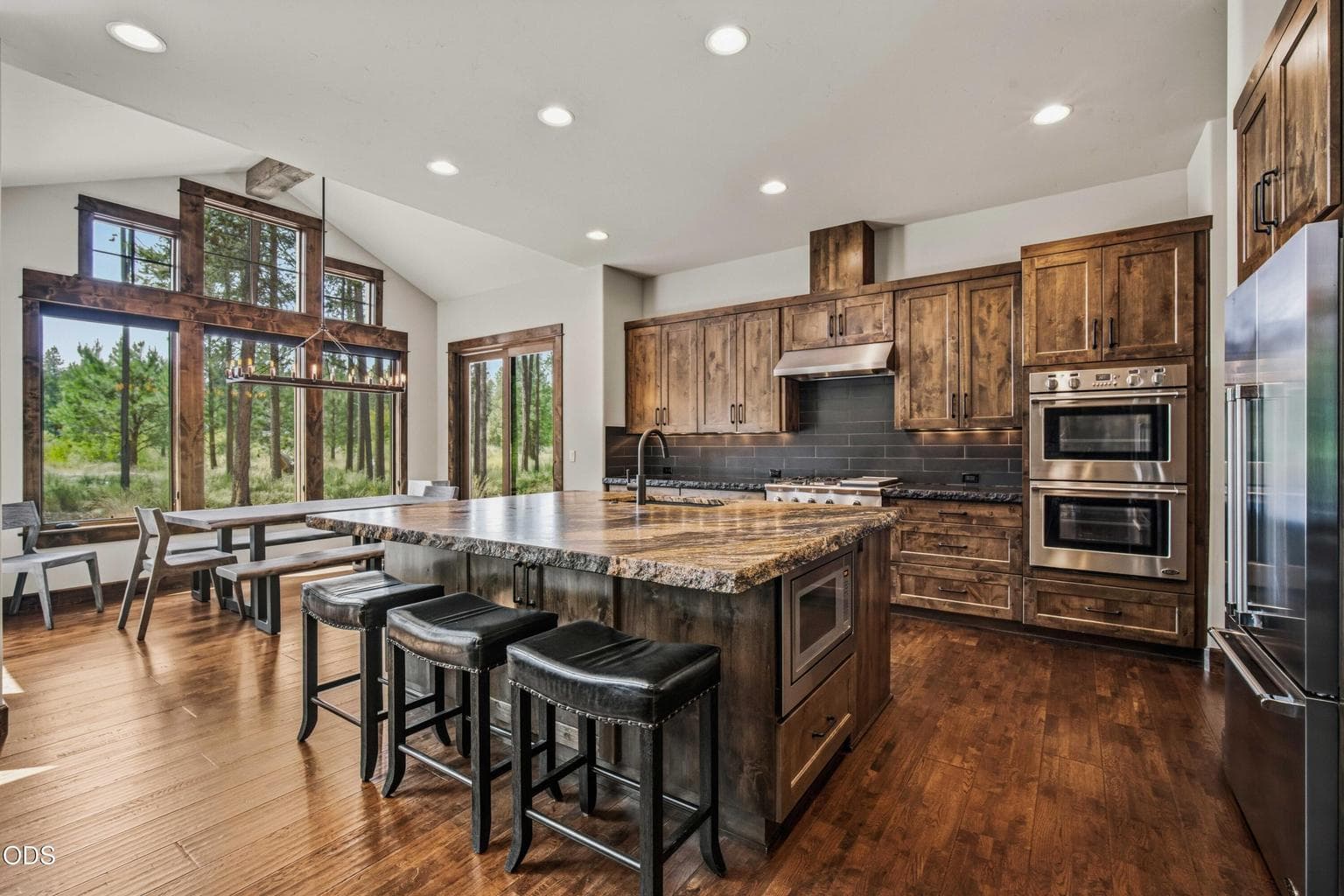 The kitchen is positioned to enjoy the natural beauty outside, with generous windows drawing in views of mature ponderosa pines and the spring-fed corridor beyond.