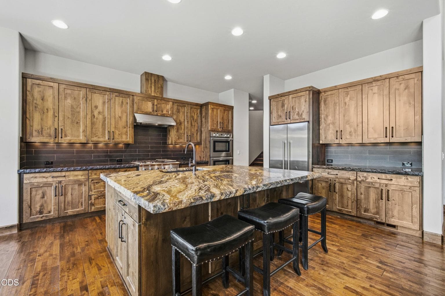The chef’s kitchen offers generous preparation space, abundant cabinetry, and a large island that naturally becomes the center of gathering within the home.