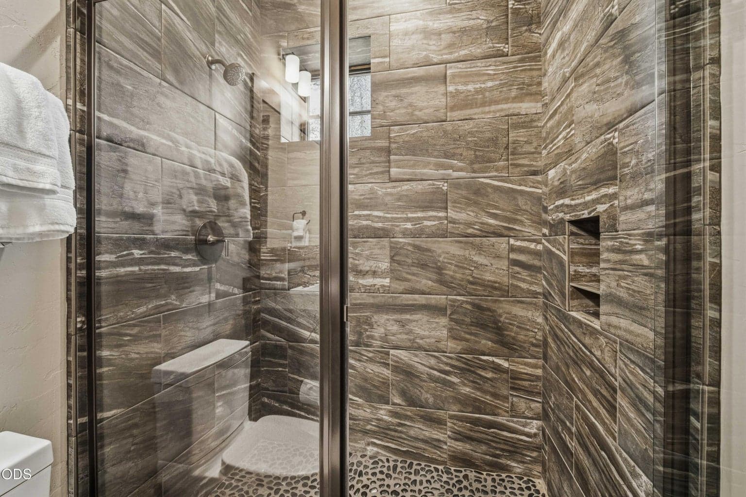 A glass-enclosed shower with richly textured tile adds a polished, spa-inspired detail to the guest suite.