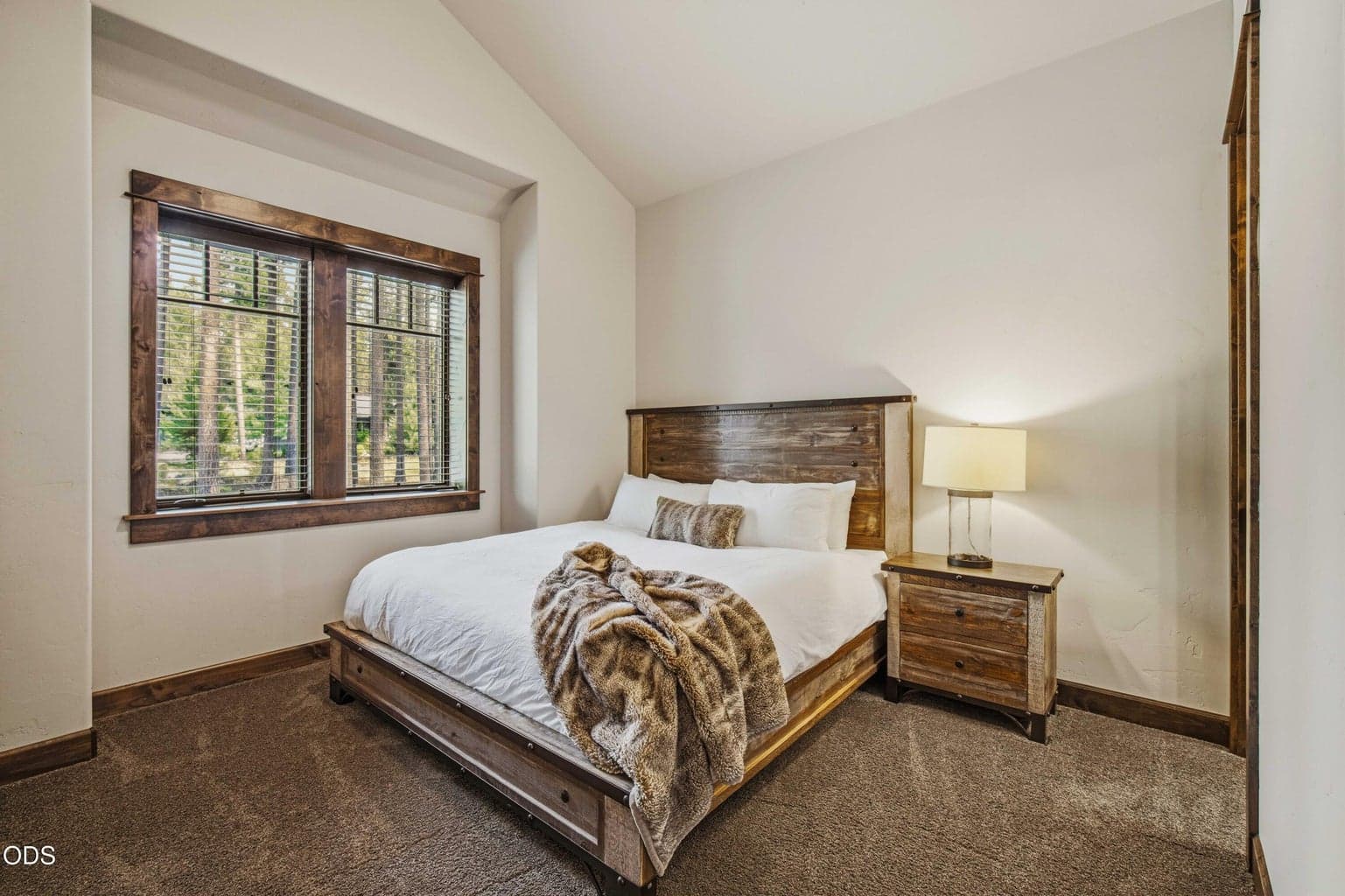 This guest bedroom offers a calm, comfortable retreat with vaulted ceilings, warm wood trim, and a soft neutral palette.