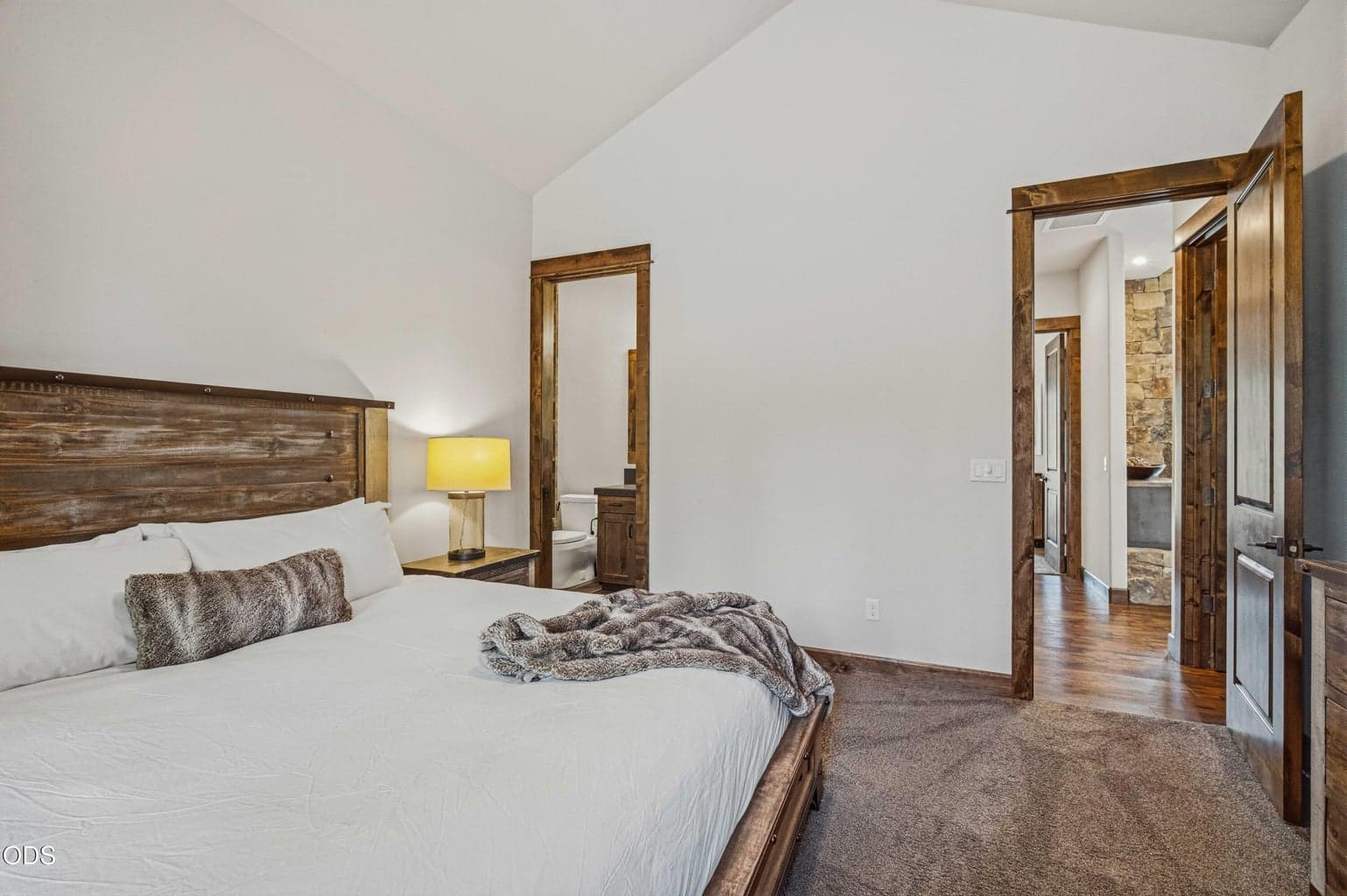 The second guest bath features wood-look tile, a glass tub-shower enclosure, and warm cabinetry for a clean and elevated suite experience.