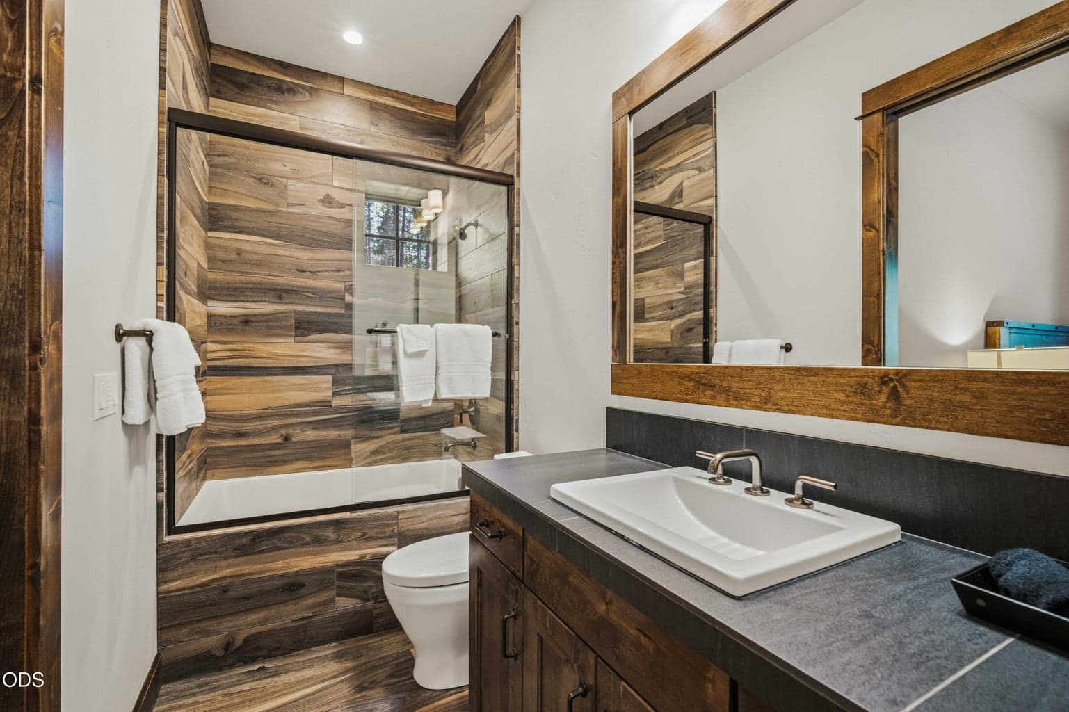 A tub-shower combination with wood-look tile provides both function and design continuity, ideal for guests or extended stays.