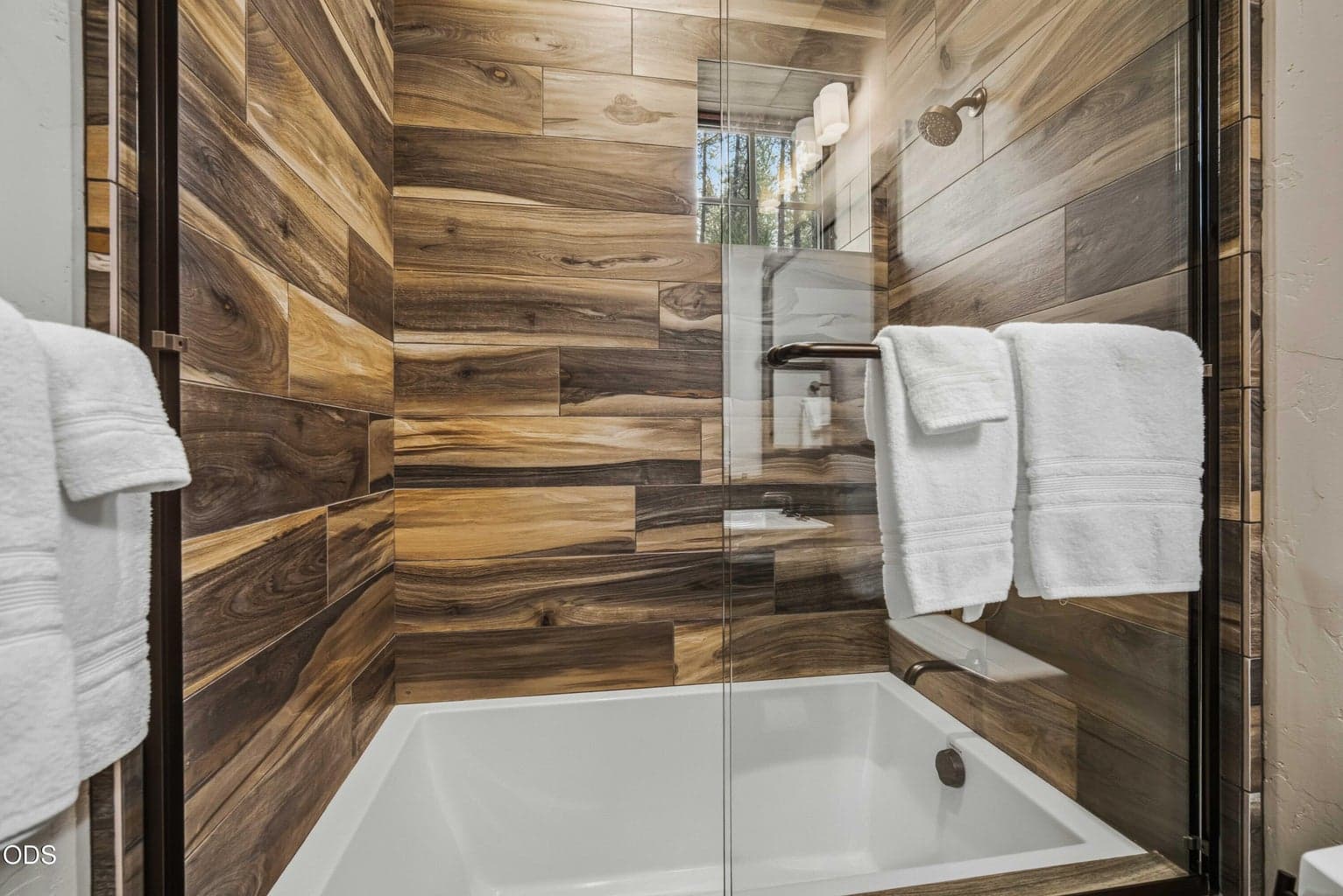 The tub surround brings natural wood tones into the bath, echoing the textures found throughout the home.