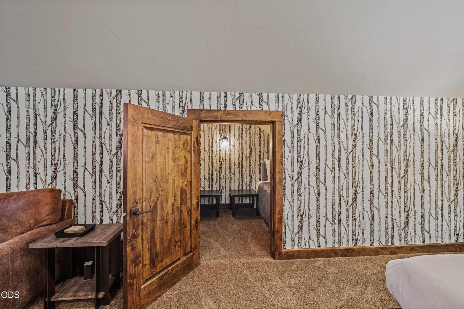 A cozy sleeping nook within the upstairs bonus room adds privacy and charm, with birch-inspired wall detail and warm wood trim.