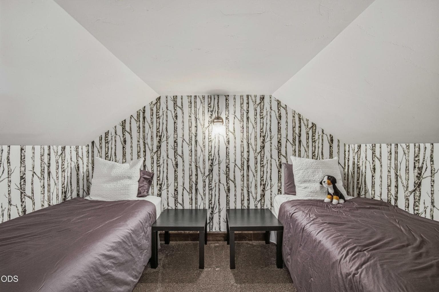 Twin beds and a playful woodland wall detail create a tucked-away upstairs sleeping area suited to guests, children, or additional flexibility.