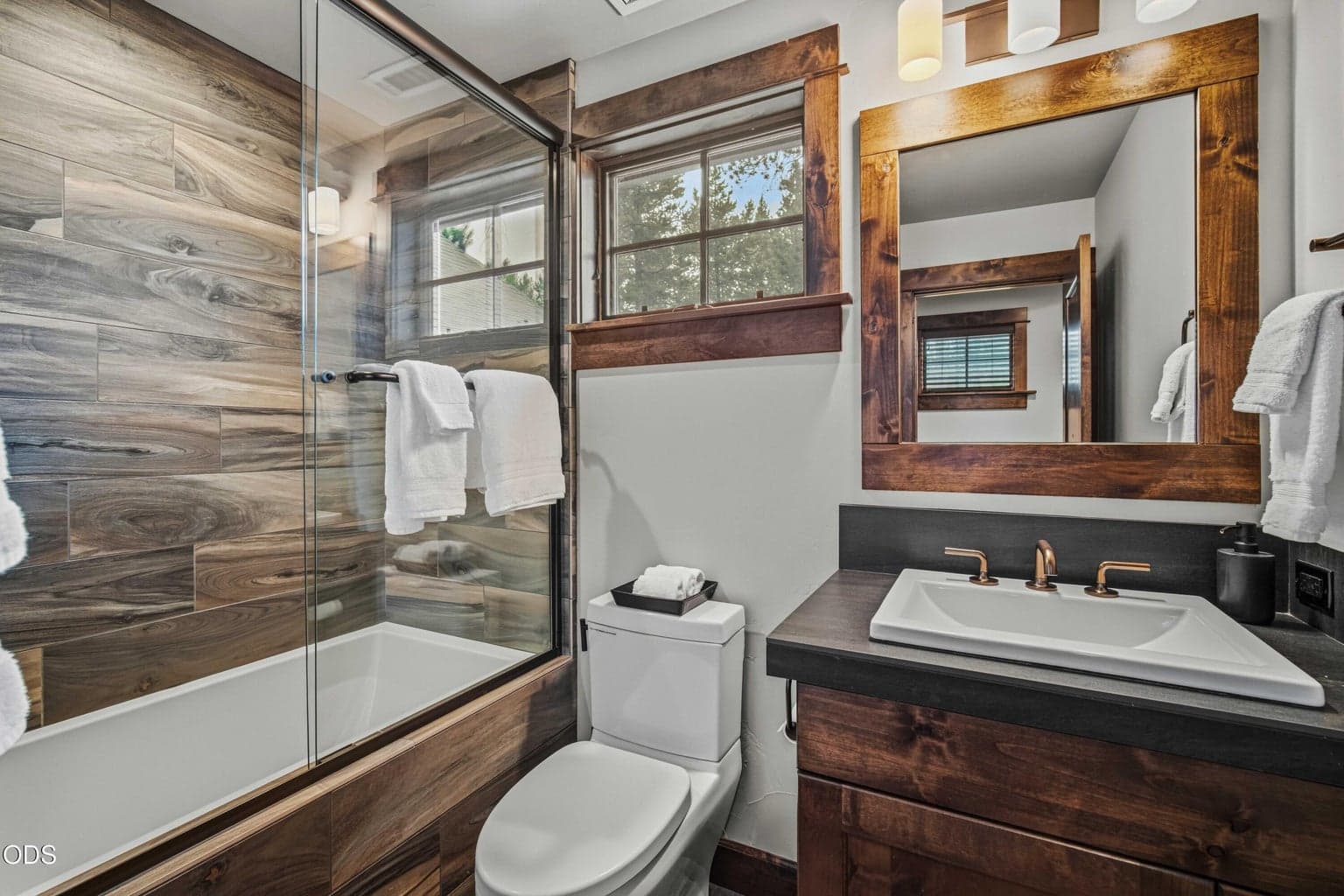 The upstairs bath supports the bonus room and fourth bedroom area, with wood-look tile, warm cabinetry, and a polished, cohesive design.