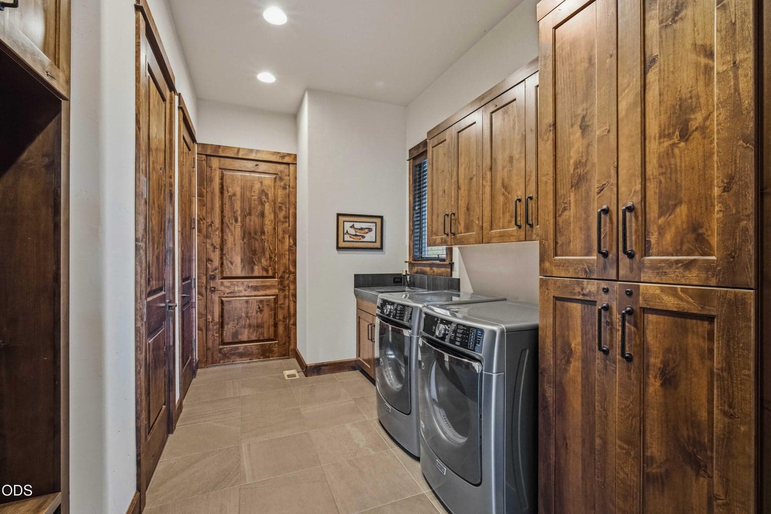 The laundry room adds practical luxury with generous cabinetry, counter space, a utility sink, and warm finishes that continue the home’s elevated style.