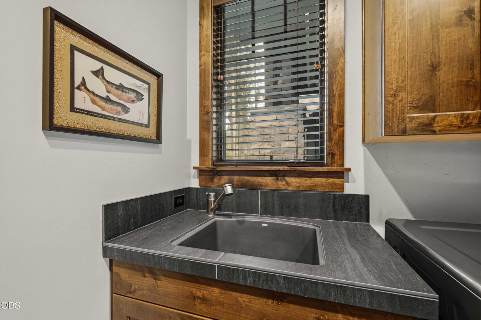 Even the utility spaces are thoughtfully finished, with a deep sink, tile counter, wood cabinetry, and natural light.