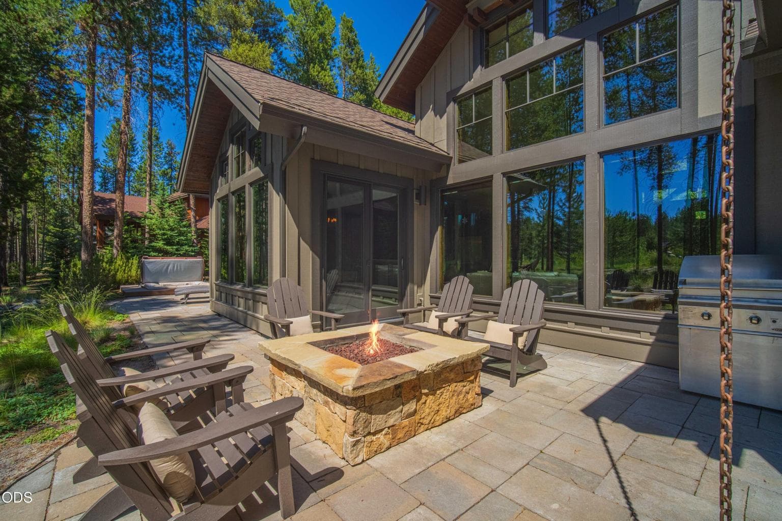 The patio extends the living experience outdoors, with a stone fire pit, generous seating, and direct connection to the natural corridor.