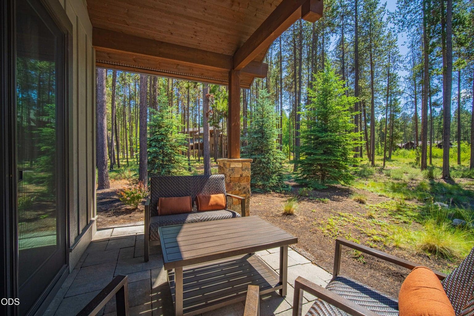A covered patio seating area invites quiet mornings, afternoon shade, and relaxed evenings while looking out across protected open space and mature trees.