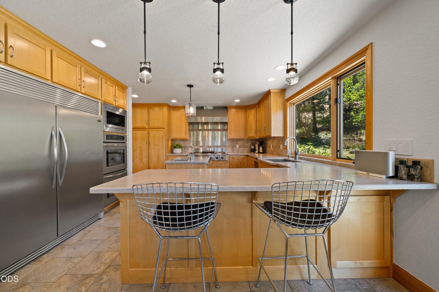 An efficient Chef's Kitchen with ample counter space, Dacor 6-burner cooktop and 32" side by side refrigerator and freezer.
