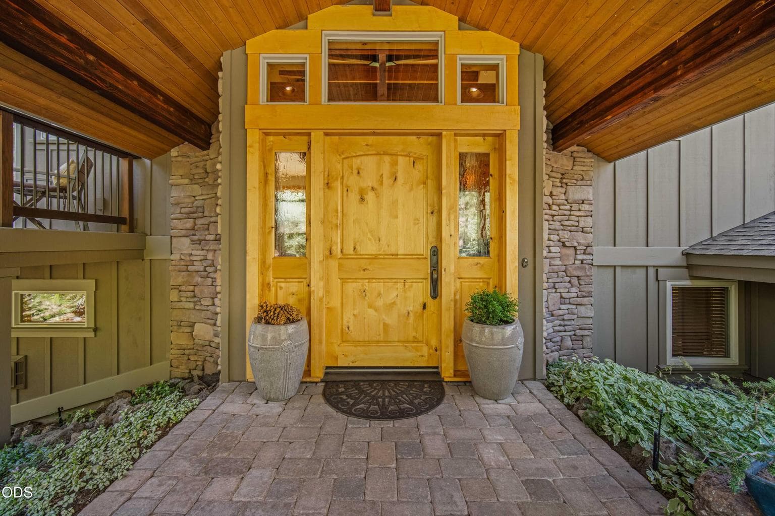 A beautifully crafted wood entry door with sidelights and transom windows reflects the quality, craftsmanship and natural materials found throughout this original-owner Sunforest home.