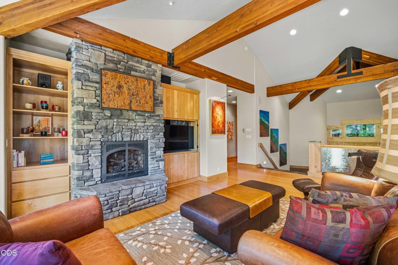 Custom wood cabinetry surrounds the floor-to-ceiling stone fireplace, providing display space, concealed storage and an integrated media center within the heart of the home.