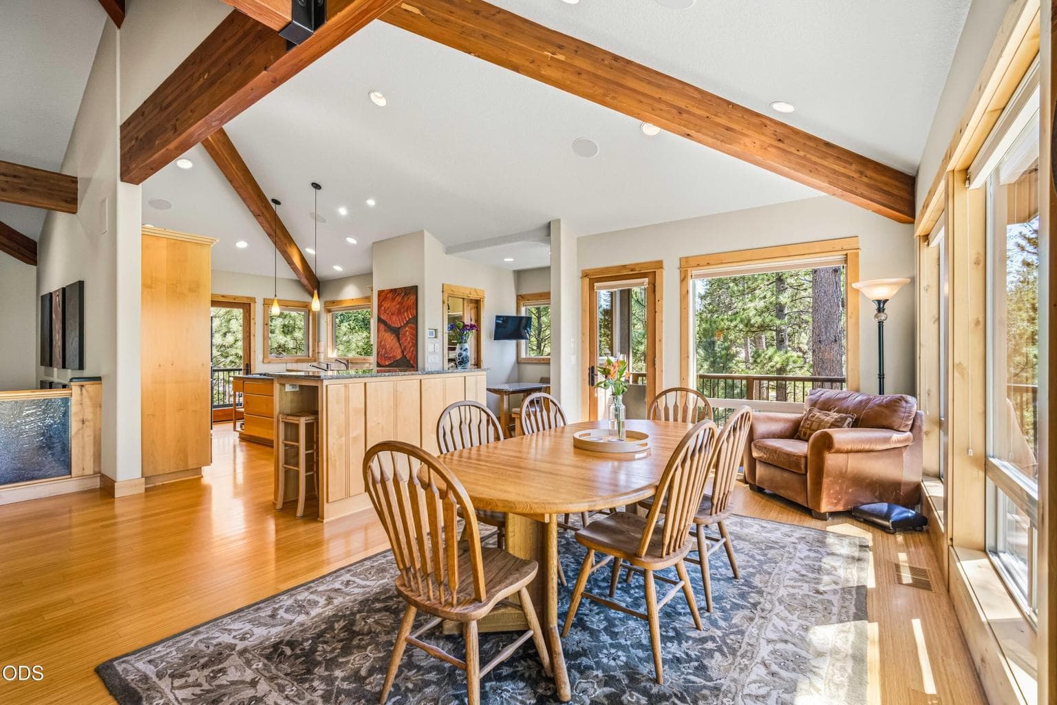 Framed by large windows and a vaulted ceiling, the dining area is oriented toward the forest and Mount Bachelor, with immediate access to the upper deck for indoor-outdoor dining and mountain-view sunsets.
