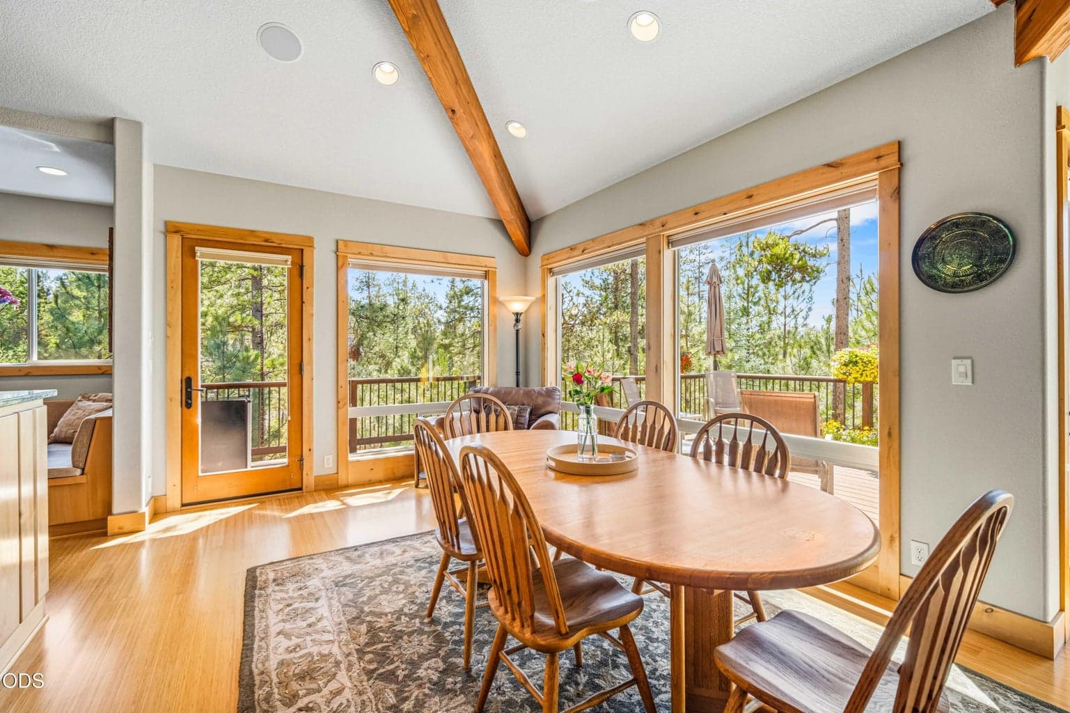 The dining area flows naturally into the great room while retaining its own sense of place, surrounded by windows, exposed beams and views across the upper deck toward the forest and Mt. Bachelor.