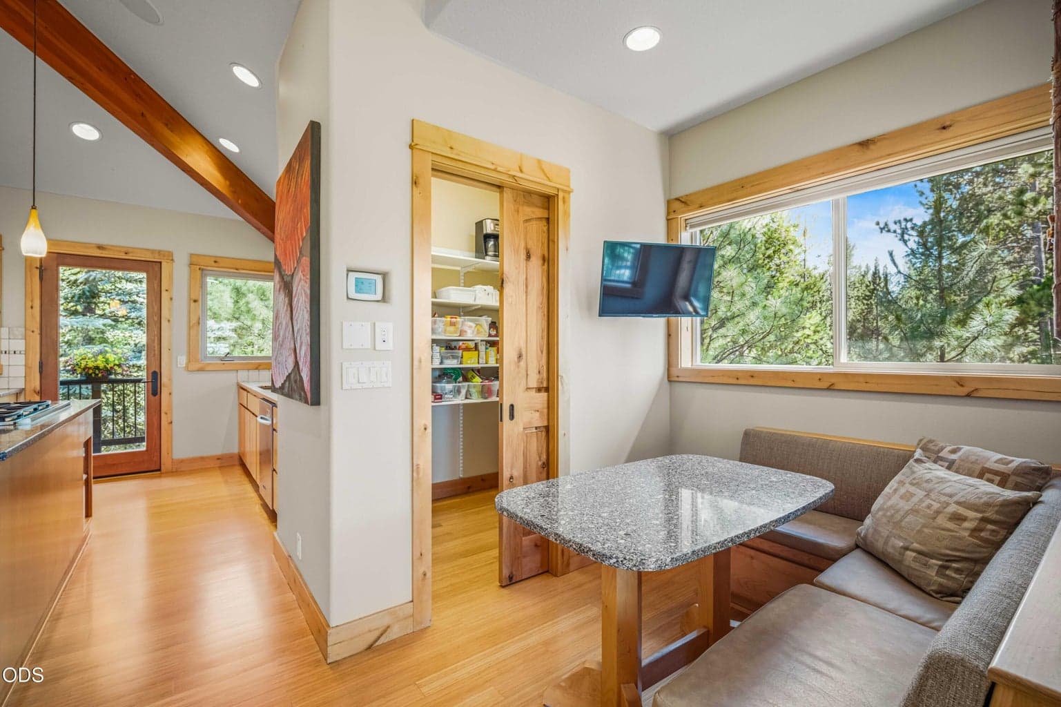 A built-in breakfast nook creates a comfortable informal dining space beside the kitchen, complemented by a walk-in pantry, large windows and a compact wall-mounted television.