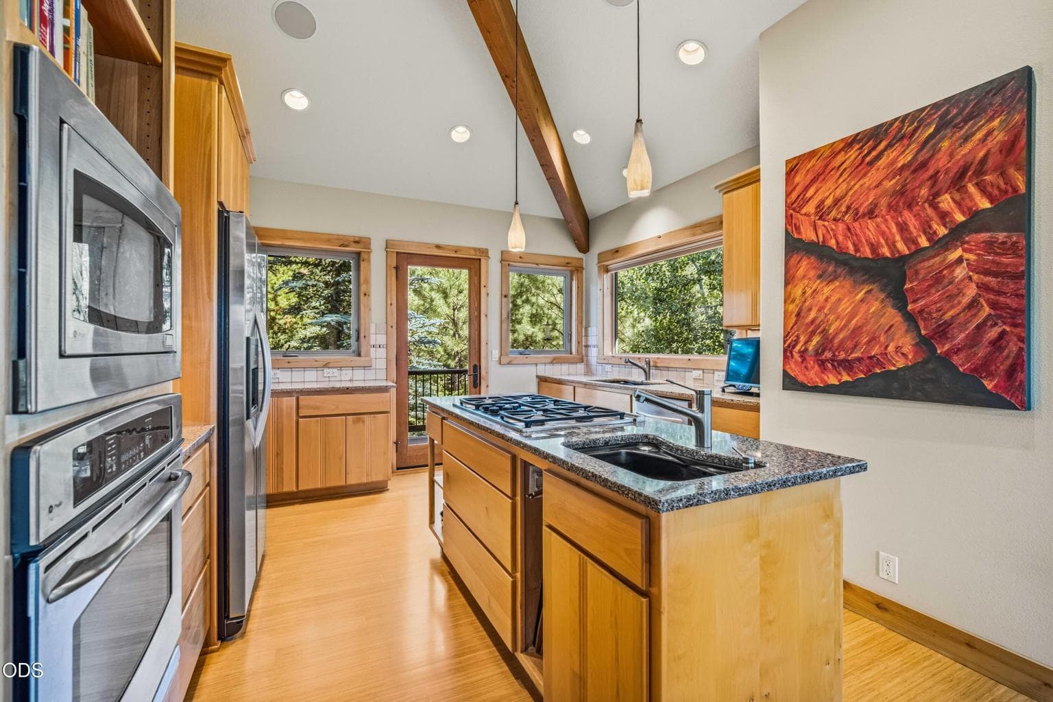 A gas cooktop and preparation sink are positioned within the central island, allowing the cook to remain connected to the adjoining dining and living areas while enjoying excellent workspace.