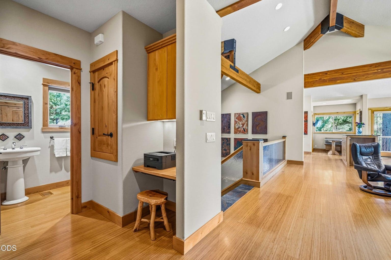 A convenient powder room and small built-in work area are positioned near the primary living spaces, providing practical functionality without interrupting the open upper-level design.