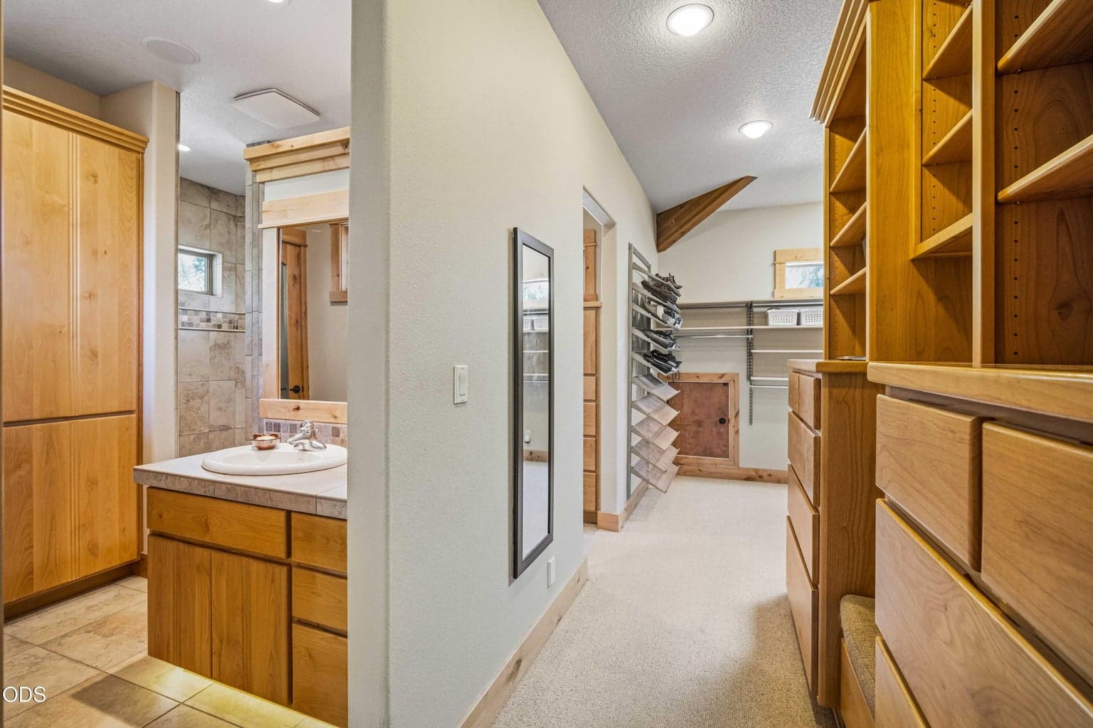 The primary suite includes an unusually generous dressing and storage area with built-in drawers, open shelving, shoe storage and a large sky-lit walk-in closet.