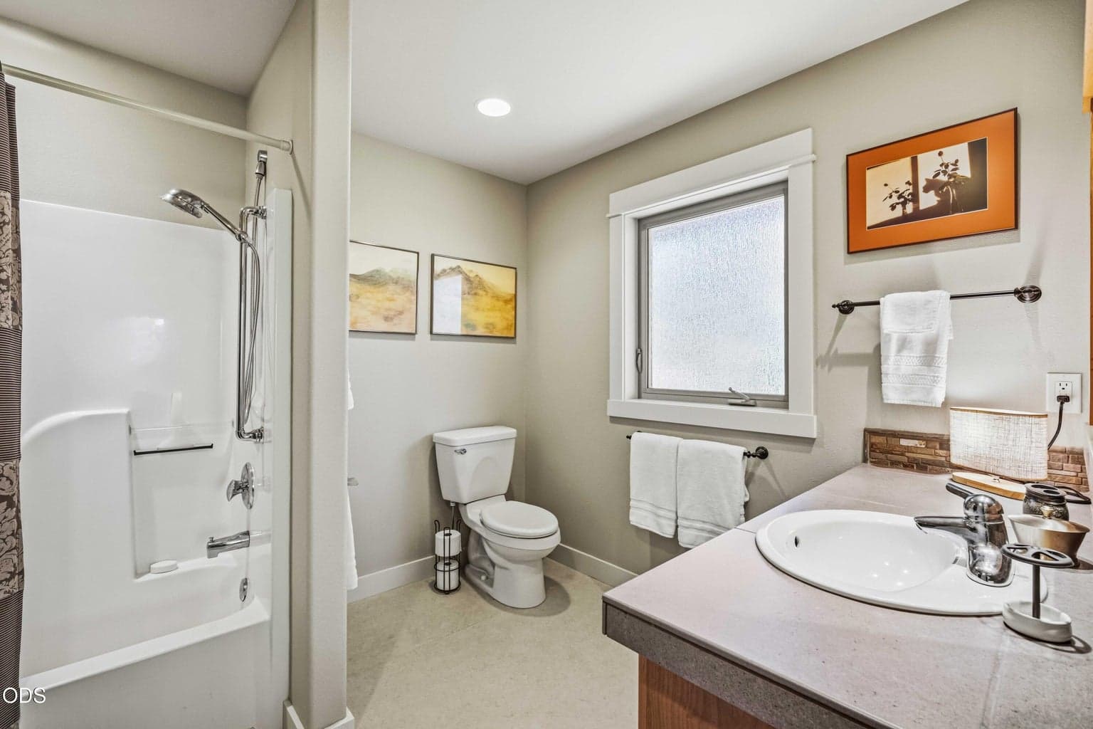 The private ensuite bath serving this lower-level guest suite includes a tub and shower combination, handheld fixture and natural light. This thoughtful arrangement allows the bedroom to function as one of two complete guest suites on the lower level.