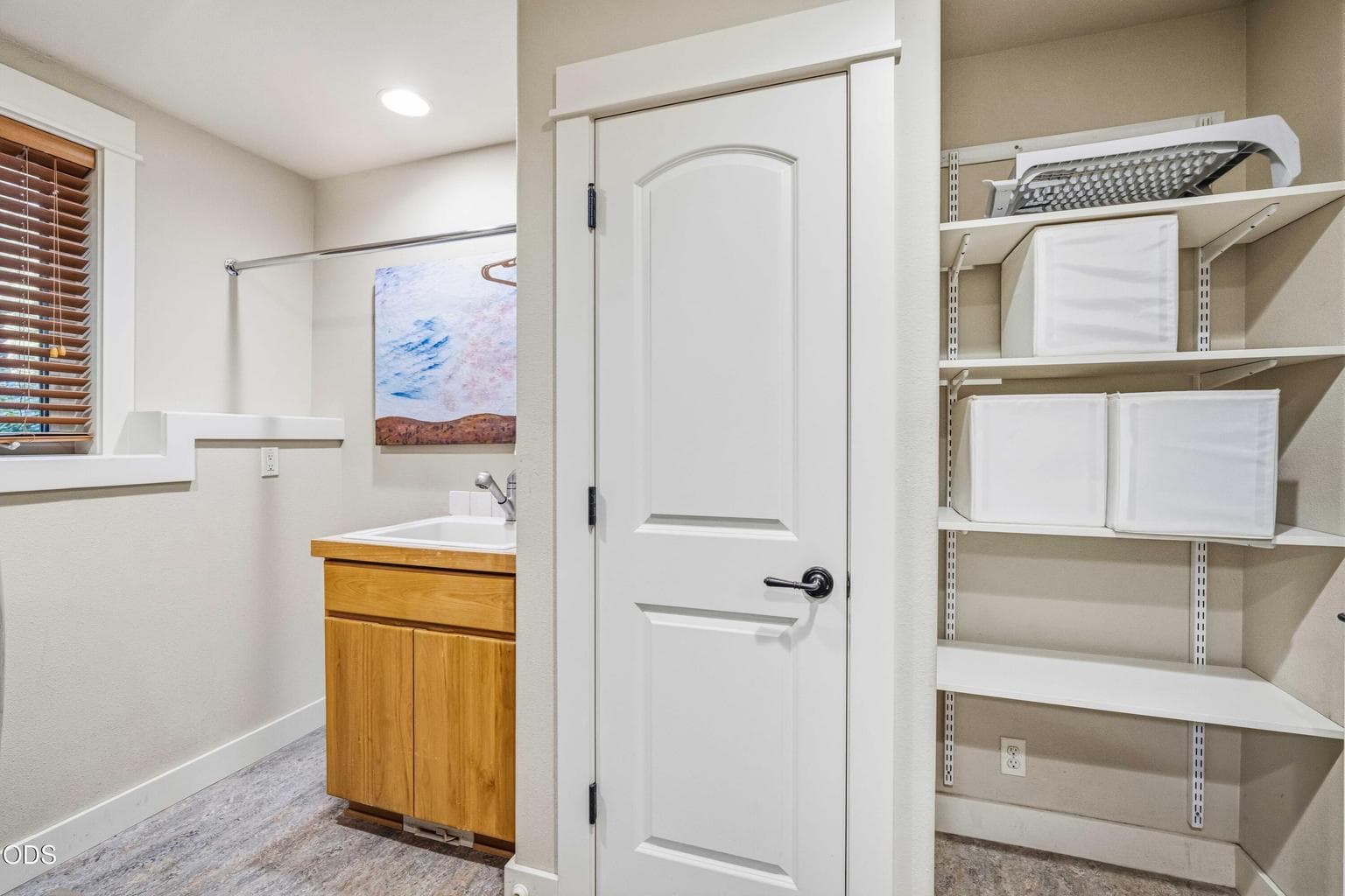 Additional shelving, a utility sink and open storage make the laundry room highly functional for linens, supplies, outdoor gear and the practical needs of a large residence.