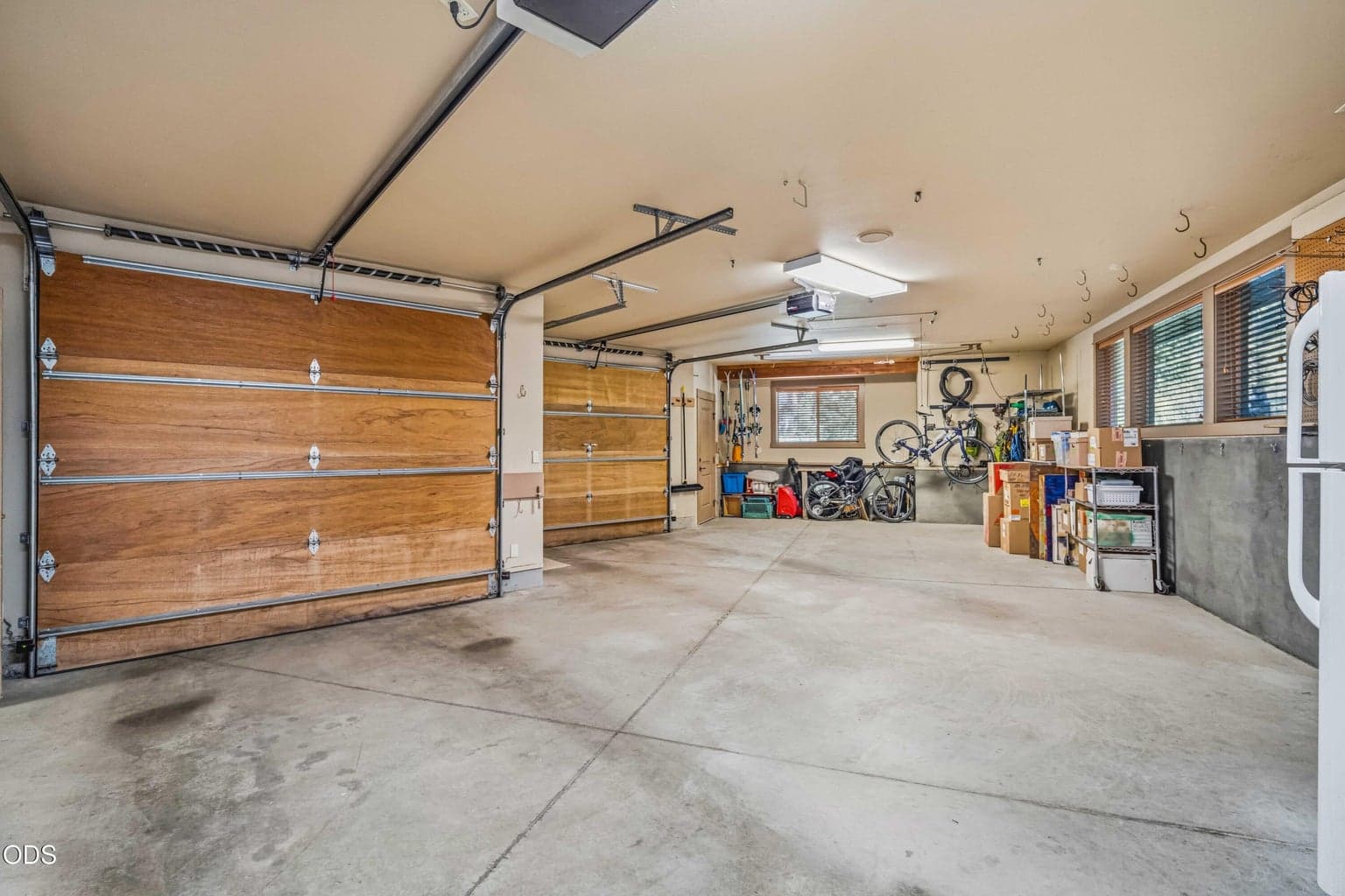 The substantial three-car garage offers broad parking capacity, high ceilings, numerous storage hooks, windows and direct connections to additional work and utility areas.